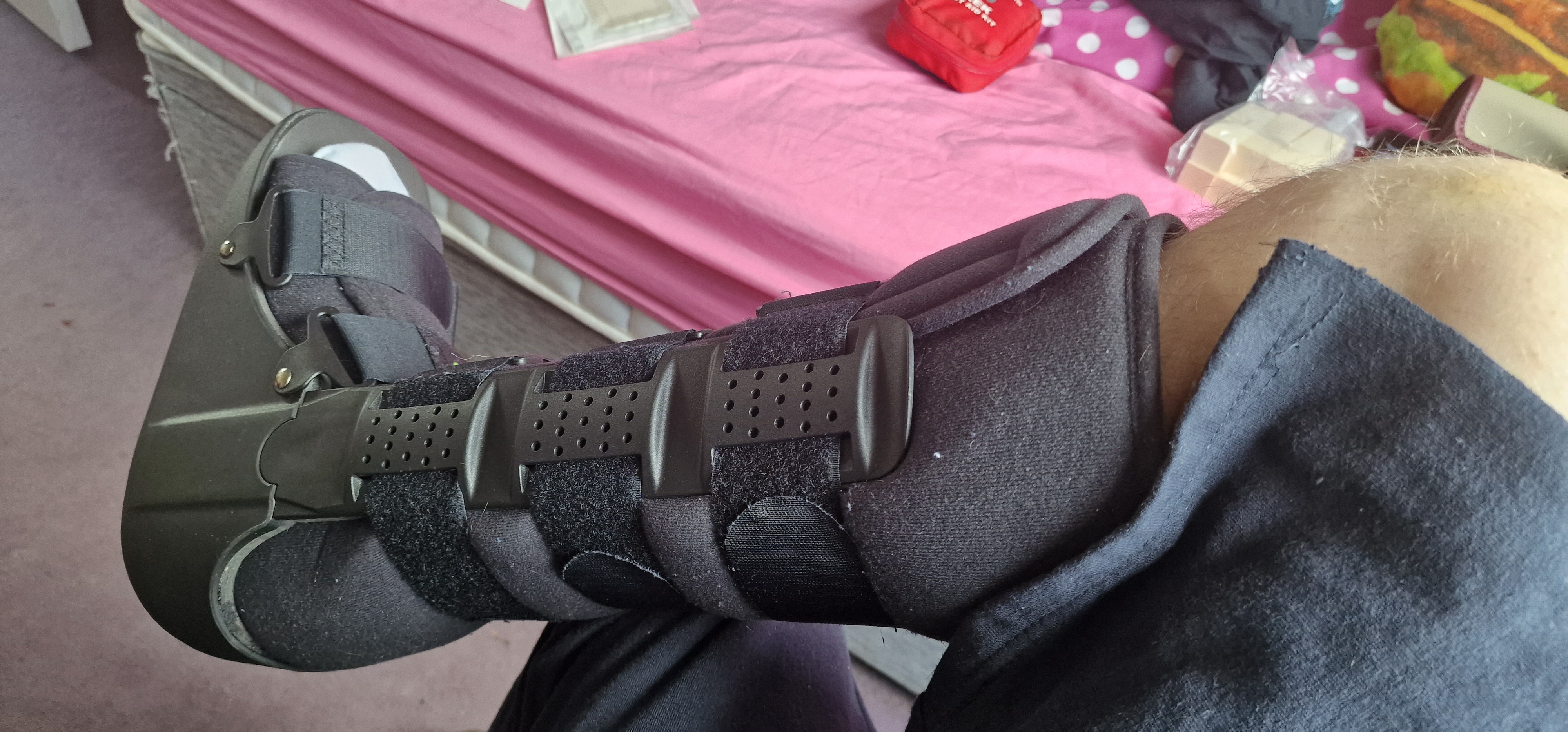 A large black boot on a right foot is shown. The boot has rigid plastic supports with a foam lining and is held in place with large Velcro straps